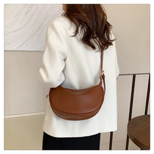 Brown leather half-moon crossbody bag shown on model for size and style reference