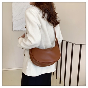 Detail view of a vintage brown leather crescent bag worn as a shoulder crossbody