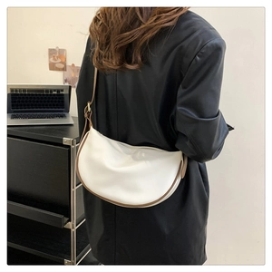 Detailed side view of a white crescent moon shoulder bag with brown leather trim