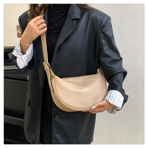 Detail of adjustable strap with gold metal buckle on beige crescent crossbody bag