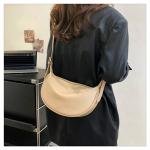 Model wearing a chic beige hobo bag with adjustable strap and sleek zipper closure