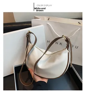 Detail of soft leather hobo bag in white and brown with adjustable strap and gold buckle