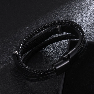 Men's double-layer black braided leather bracelet with magnetic metal clasp on a black case