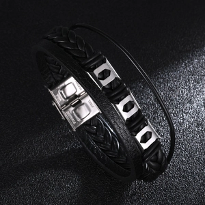 Macro detail of men's multilayer leather braid bracelet with engraved stainless steel clasp