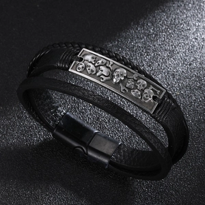 Detail eines mehrlagigen schwarzen Lederarmbands mit Totenkopf-Metall-Charm und Magnetverschluss