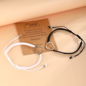 Gros plan de bracelets de couple tressés réglables avec pendentifs cœur sur une carte cadeau