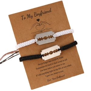 Handmade woven couple bracelets with stainless steel razor blade charms on a card