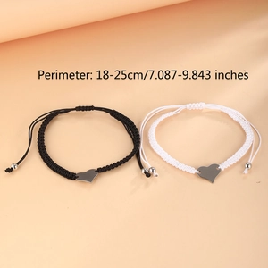 Close-up of woven couple bracelets with silver heart charms and adjustable cords