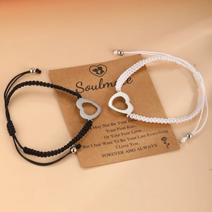 Close-up of woven couple bracelets with hollow heart charms on a Soulmate card