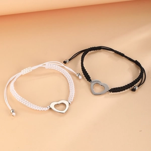 Close-up of heart-shaped hollow charms on adjustable woven bracelets for couples