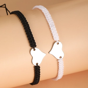 Close-up of black and white braided couple bracelets with polished heart-shaped charms