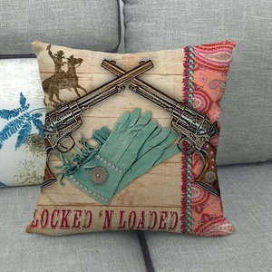 Detail of vintage western denim pillow cover with revolvers on a soft grey sofa