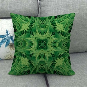 Linen cushion cover with green geometric fern leaf patterns on a grey fabric sofa