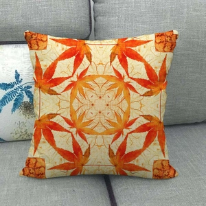 Close-up of linen pillowcase with orange maple leaf pattern on a grey sofa
