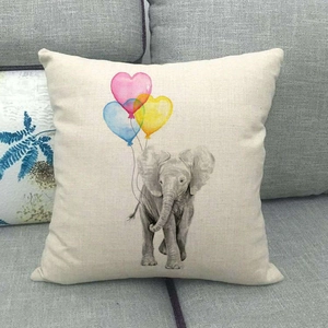 Close-up of linen cushion cover showing elephant and heart balloons on a sofa