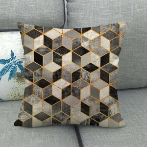 Detail of 3D geometric marble pillowcase with gold lines on a grey sofa