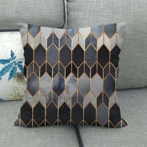 Detail of a modern geometric pillow case with blue marble pattern and gold lines on a sofa