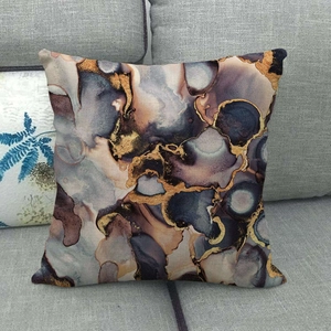 Detail of marble pattern cushion cover with gold fluid art on grey fabric sofa