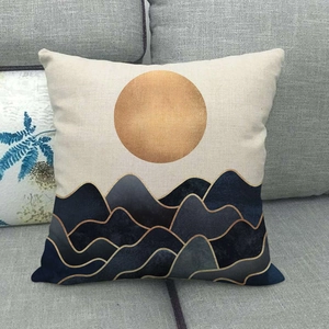 Abstract linen pillow cover with golden sun and blue mountains on grey sofa