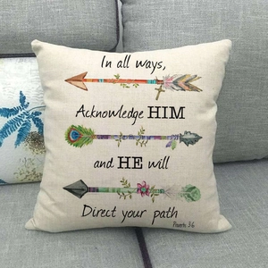 Close-up of bohemian linen pillowcase with arrows and religious text on grey sofa