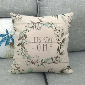 Détail d'une housse de coussin en lin avec motif floral et texte LET'S STAY HOME