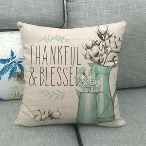 Housse de coussin en lin avec motif coton et arrosoir posée sur un canapé gris