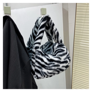 Detail of soft faux fur zebra print hobo bag featuring silver zipper and plush texture