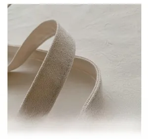 Close-up of durable beige canvas tote bag handles with precise reinforced stitching detail