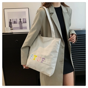 Detail of colorful STUFF embroidery on beige canvas tote bag with thick cotton fabric