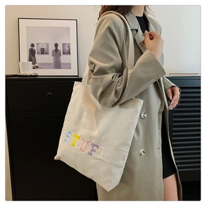 Close-up of a white canvas tote bag featuring colorful STUFF embroidery for daily use