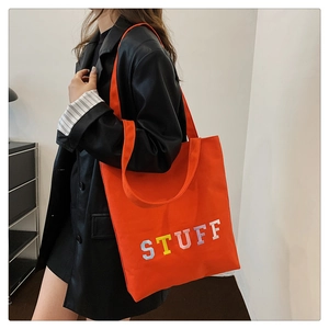 Detailed view of orange canvas tote bag with colorful STUFF embroidery on front