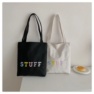 Detail of black and cream canvas tote bags with colorful 3D STUFF embroidery