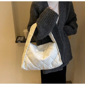 Détail d'un sac cabas matelassé blanc avec motif de losanges porté par un mannequin