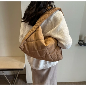 Gros plan sur un grand sac porté épaule matelassé marron avec coutures en losanges et texture