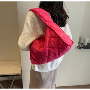 Détail d'un sac cabas matelassé rouge rose avec motif à losanges sur l'épaule du mannequin