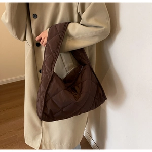 Détail d'un grand cabas matelassé marron porté avec un manteau en laine beige élégant