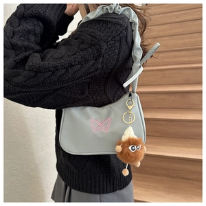Detail view of light blue shoulder bag with pink butterfly embroidery and ruffled strap