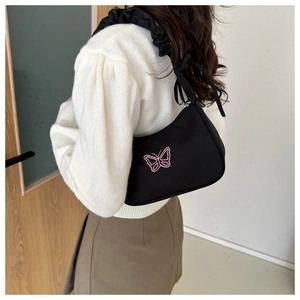 Detail of black underarm bag featuring pink butterfly embroidery and ruched strap