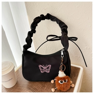 Detail of black crescent shoulder bag with pink butterfly embroidery and plush charm