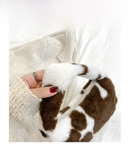 Gros plan du sac à main en peluche à motif vache avec fermeture éclair blanche