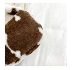 Gros plan sur un sac à main en peluche douce avec texture imprimé vache marron et blanc