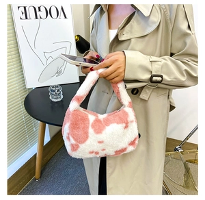 Détail du sac à main en peluche à motif vache rose et blanc dans un studio de mode