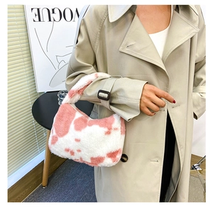 Gros plan d'un sac à main en peluche à motif vache rose porté avec un trench beige