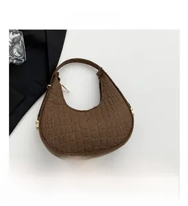 Détail du sac baguette marron foncé avec texture crocodile embossée et accents dorés