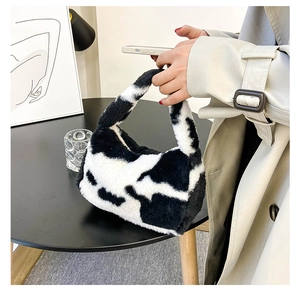 Détail d'un sac à main doux en peluche à motif vache tenu par un mannequin avec style