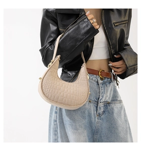 Détail du sac sous le bras beige à motif croco avec fermoirs dorés sur le mannequin