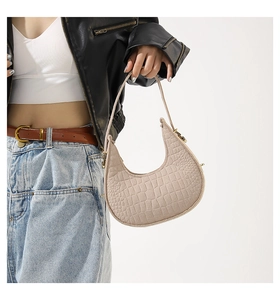 Détail du sac baguette à motif crocodile porté par un mannequin en tenue décontractée