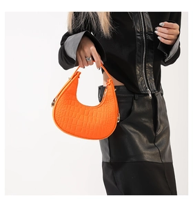 Gros plan du sac demi-lune orange vif avec motif crocodile et détails de zip métallique