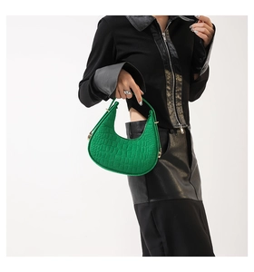 Détail du sac croissant vert vif avec motif crocodile et fermeture éclair métallique