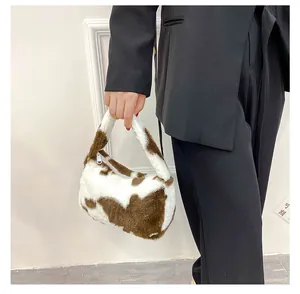Détail du sac à main en peluche douce avec motif vache marron et blanc élégant